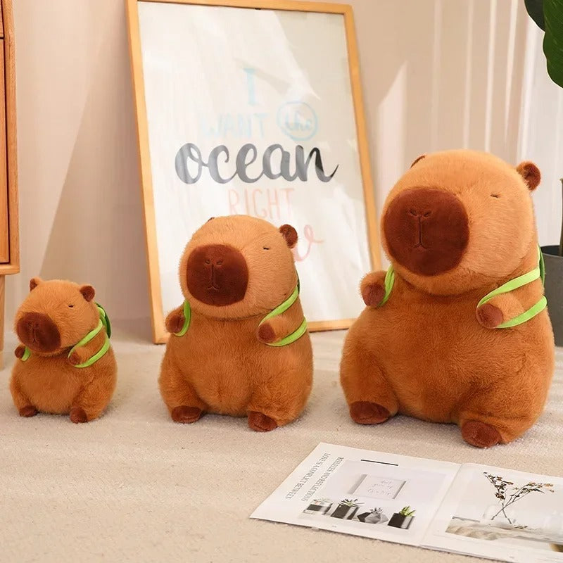 Three capybara plush toys lined up in small, medium, and large sizes with bright green turtle backpacks – perfect stuffed animal gift set for kids or collectors.