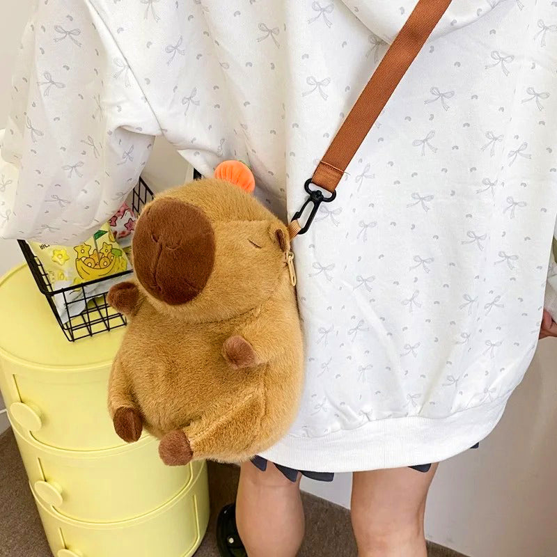 Small capybara crossbody backpack worn on back of girl in white hoodie