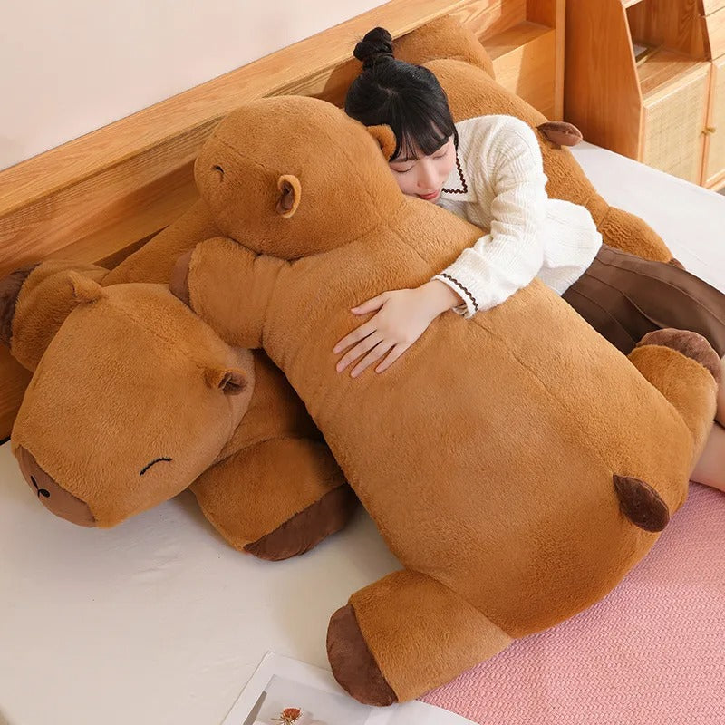 Person lying on a giant capybara body pillow plush, oversized stuffed animal for sleep and snuggles.