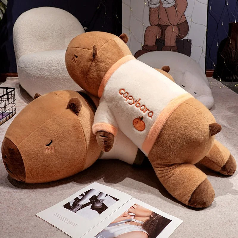 Two giant capybara plush stuffed animals in pajamas stacked on floor, oversized cuddle pillows.