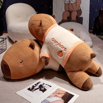 Two giant capybara plush stuffed animals in pajamas stacked on floor, oversized cuddle pillows.
