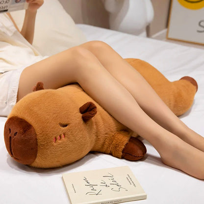 Girl lounging with large capybara plush toy used as a leg pillow for cozy and supportive relaxation.