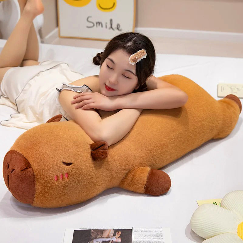 Girl hugging extra-large capybara plush pillow on bed, highlighting its squishy and oversized design.