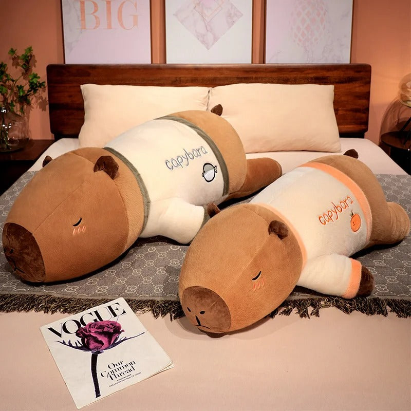Two pajama party capybara plush toys lying on bed, oversized stuffed animals for sleep and comfort.