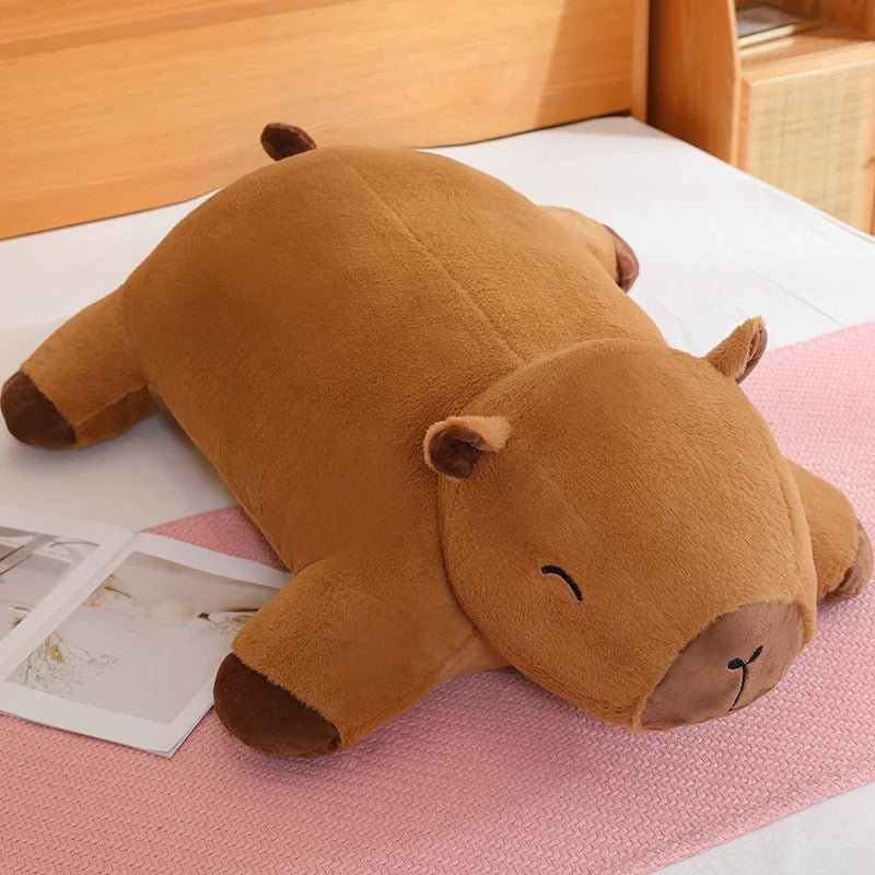 Capybara plush pillow Jolly Dreams edition placed on a bed, soft and cute stuffed animal.