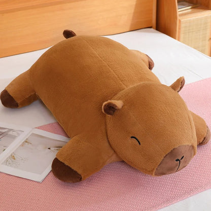 Capybara plush pillow Jolly Dreams edition placed on a bed, soft and cute stuffed animal.