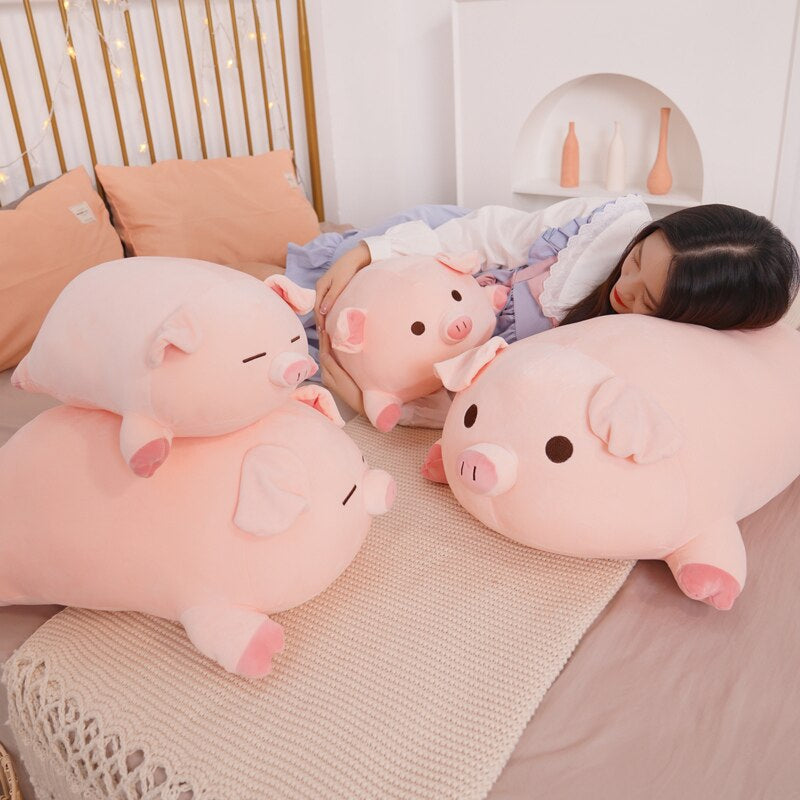 A person resting comfortably on a bed surrounded by a variety of pink kawaii squishy piggy plushies, showing their use as soft sleeping companions.