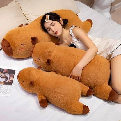Girl snuggling with three capybara plush toys in bed, emphasizing life-size scale and comfort.