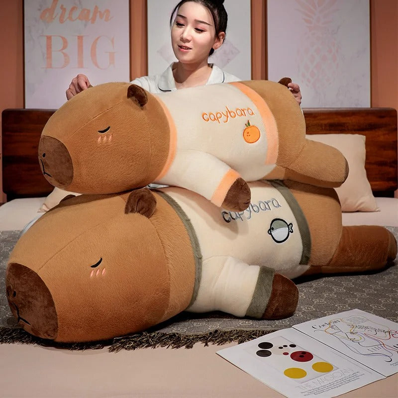Woman holding and hugging large pajama party capybara plush body pillow stuffed toy.