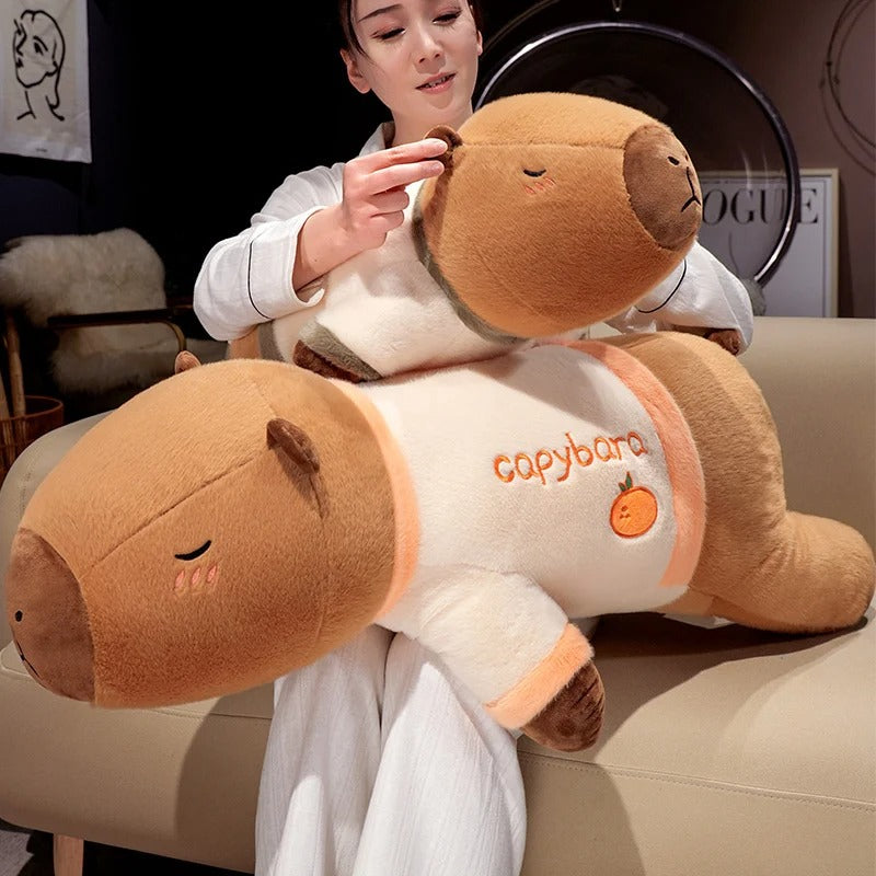 Woman hugging giant capybara plush pajama edition stuffed animal, soft cuddle pillow toy.