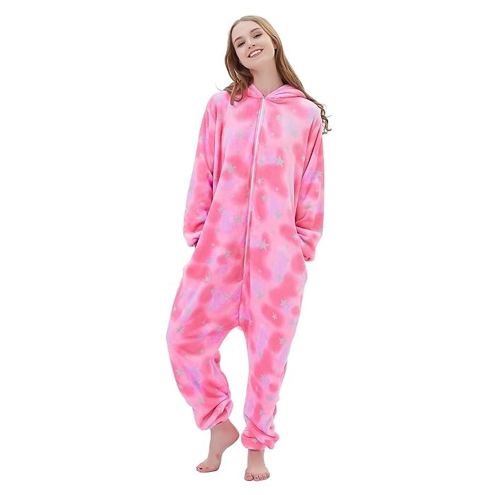 Relaxed pose in pink fleece unicorn onesie for adults featuring pastel star pattern.